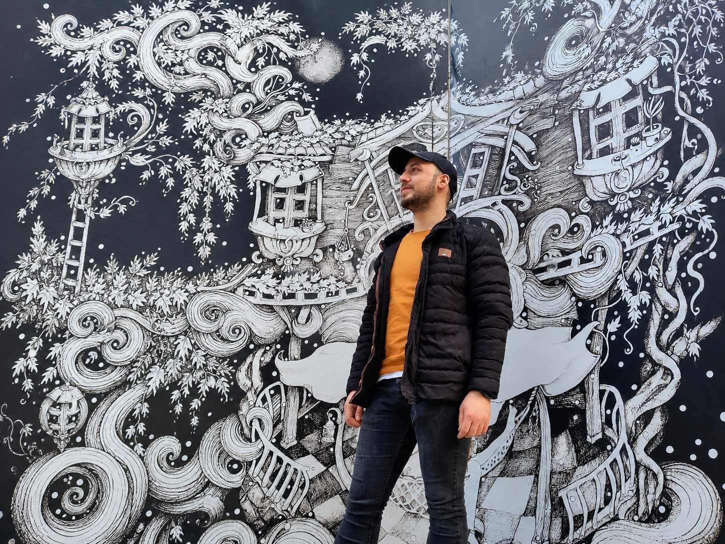 Basel in front of a large black-and-white mural.